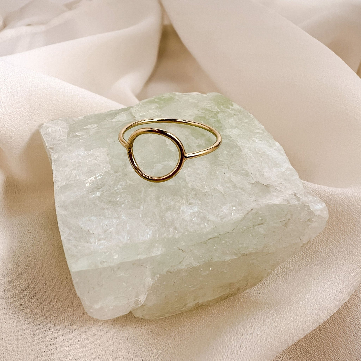 highly polished, dainty 14KGF hollow circle stacking ring displayed on aqua colour gemstone