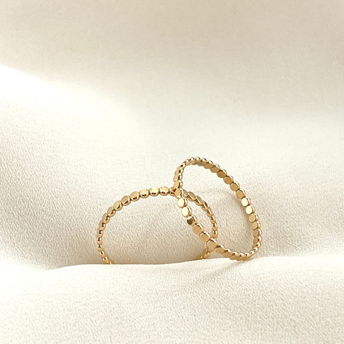 14K Gold filled dot ring on cream coloured background. The dot ring is a series of uniform gold circles joined together to create a circle finger ring. Highly polished giving a glorious shine  Edit alt text