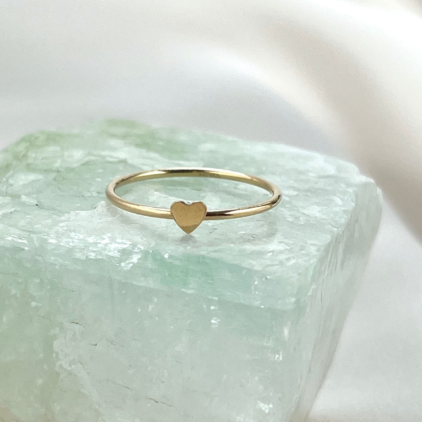 14K Gold filled simple band ring with tiny 2mm cut out heart shape on top. Gold heart ring is sitting onto of shiny  mint coloured crystal