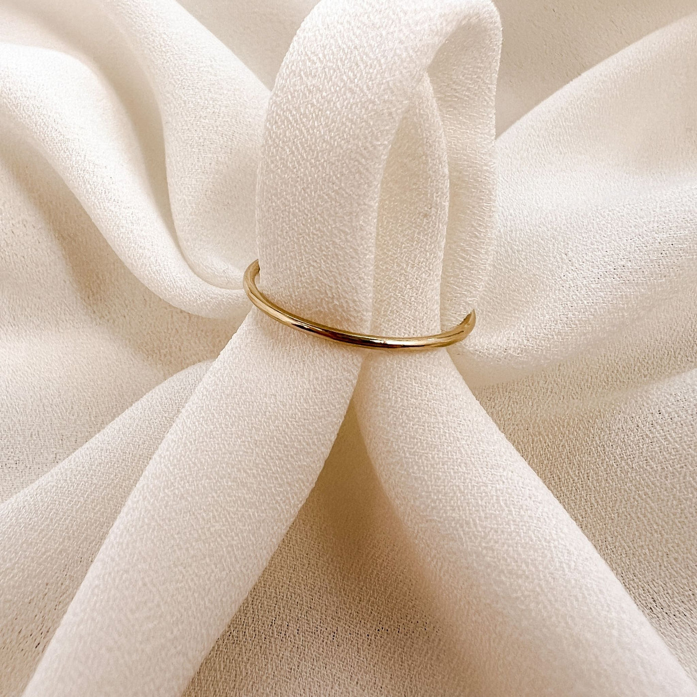 Simple 14Kgold filled 1mm band ring on cream coloured fabric 