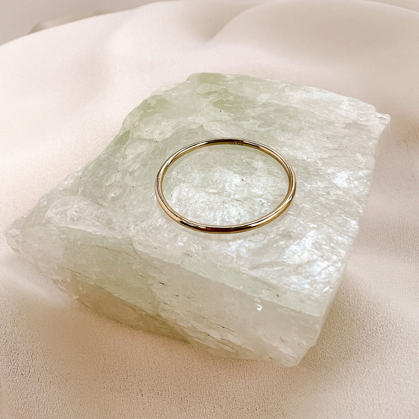 Simple 14Kgold filled 1mm band ring displayed onto of a qua coloured gemstone