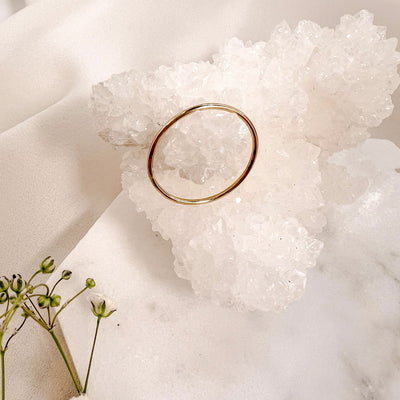 Simple 14Kgold filled 1mm band ring leaning on  white sparkly crystal geode