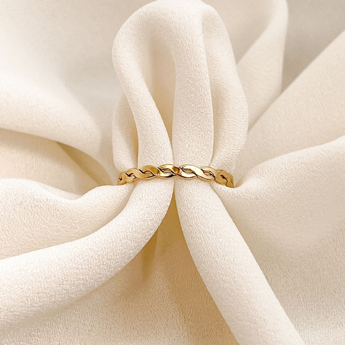 Highly polished 14K gold filled double braided women's stacking ring on cream coloured background