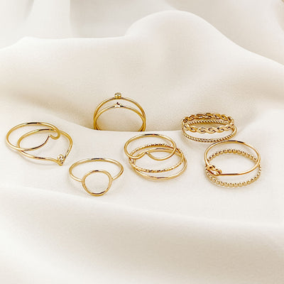 Assortment of 12 minimalist 14KGF stacking rings displayed on cream coloured fabric