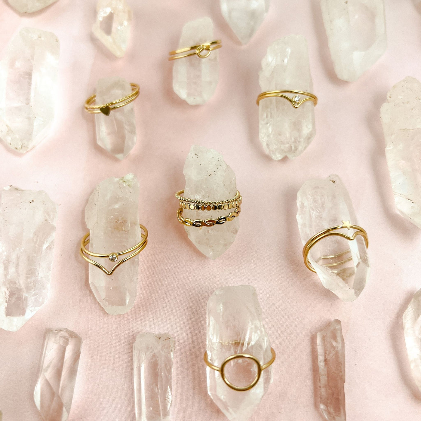 Assortment of differing styles of minimalist and dainty women’s stacking rings displayed on several quarts crystal points