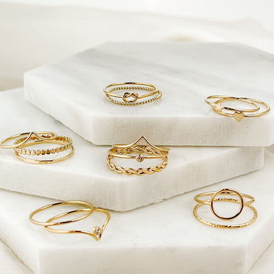assortment of  differing 14K gold filled minimalist  stacking rings on 3 tiered marble hexagon shaped tiles