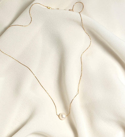 small white fresh water pearl bead strung on dainty glimmering gold snake chain necklace